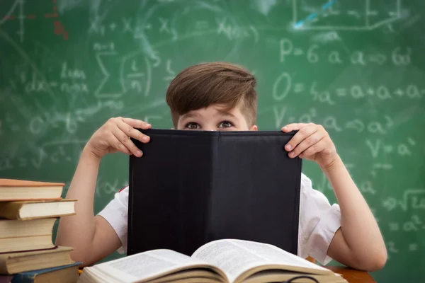 Funny schoolboy hiding behind book — Stock Photo, Image