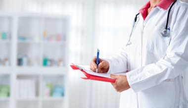 Doktor hastane karton üzerinde yazma stetoskop ile