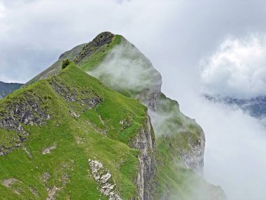 Miraculous low clouds and a mystical fog of the mountain range First and in the Schwyz Alps mountain massif, Oberiberg - Canton of Schwyz, Switzerland (Kanton Schwyz, Schweiz)
