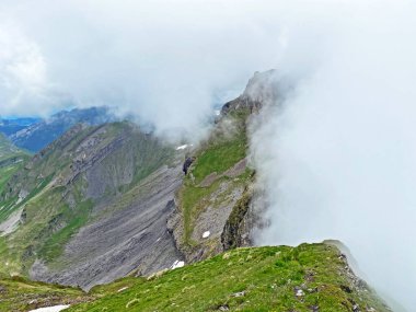 Miraculous low clouds and a mystical fog of the mountain range First and in the Schwyz Alps mountain massif, Oberiberg - Canton of Schwyz, Switzerland (Kanton Schwyz, Schweiz)