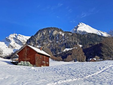 Idyllic Swiss alp dağ kulübeleri ve kışlık giysiler içinde geleneksel İsviçre kırsal mimarisi ve Obertoggenburg bölgesinde yeni bir kar örtüsü, Unterwasser - İsviçre 'nin St. Gallen Kantonu (Schweiz)