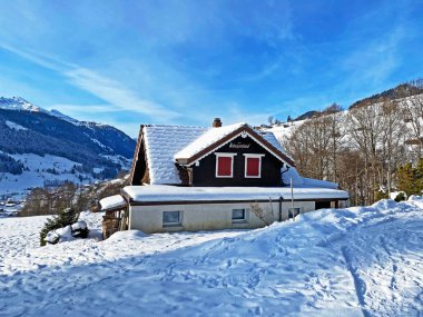 Idyllic Swiss alp dağ kulübeleri ve kışlık giysiler içinde geleneksel İsviçre kırsal mimarisi ve Obertoggenburg bölgesinde yeni bir kar örtüsü, Unterwasser - İsviçre 'nin St. Gallen Kantonu (Schweiz)