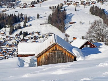 Idyllic Swiss alpine mountain huts and traditional Swiss rural architecture dressed in winter clothes and in a fresh snow cover in the Obertoggenburg region, Wildhaus - Canton of St. Gallen, Switzerland (Schweiz)