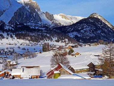 Idyllic Swiss alpine mountain huts and traditional Swiss rural architecture dressed in winter clothes and in a fresh snow cover in the Obertoggenburg region, Wildhaus - Canton of St. Gallen, Switzerland (Schweiz)
