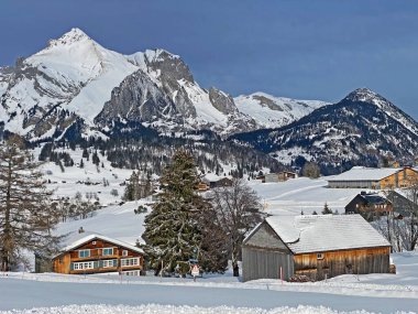 Idyllic Swiss alpine mountain huts and traditional Swiss rural architecture dressed in winter clothes and in a fresh snow cover in the Obertoggenburg region, Wildhaus - Canton of St. Gallen, Switzerland (Schweiz)