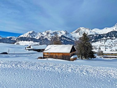 Idyllic Swiss alpine mountain huts and traditional Swiss rural architecture dressed in winter clothes and in a fresh snow cover in the Obertoggenburg region, Wildhaus - Canton of St. Gallen, Switzerland (Schweiz)