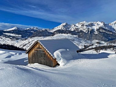 Idyllic Swiss alpine mountain huts and traditional Swiss rural architecture dressed in winter clothes and in a fresh snow cover in the Obertoggenburg region, Wildhaus - Canton of St. Gallen, Switzerland (Schweiz)