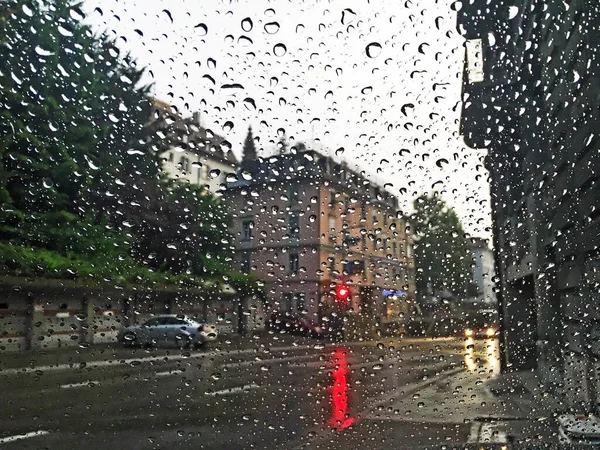 Raindrops on car glass with city silhouettes in the background out of focus - St. Gallen, Switzerland (Schweiz)