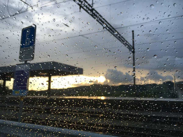 Regentropfen Auf Autoscheibe Mit Sonnenuntergang Und Bahnhof Hintergrund Unscharf Gallen — Stockfoto