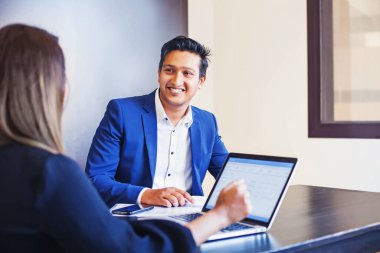 Yakışıklı Hintli adam, KYC 'de bankada ya da ofiste dizüstü bilgisayarı olan bir kadına röportaj veriyor.
