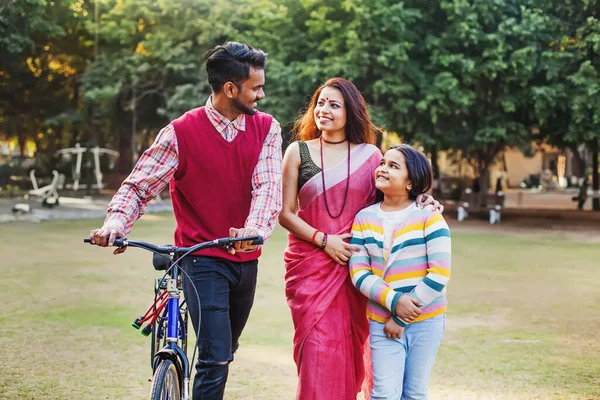 公園の屋外で自転車で歩く小さな10歳の娘を持つ美しいインドの家族 — ストック写真