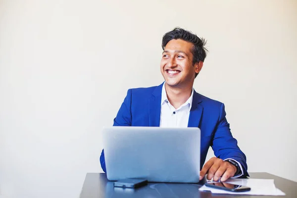 ハンサムな若いです専門家インド人男でフォーマルスーツ使用ラップトップでオフィス上の白の背景 ストック写真