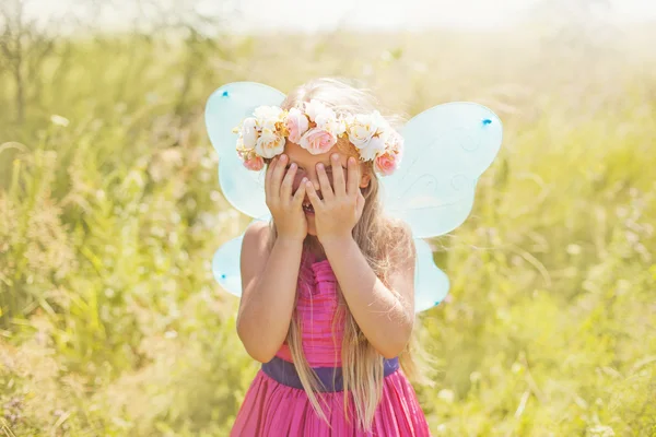 Niña en una corona de flores y alas de hadas —  Fotos de Stock