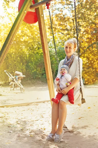 Mãe com criança montando em um balanço — Fotografia de Stock