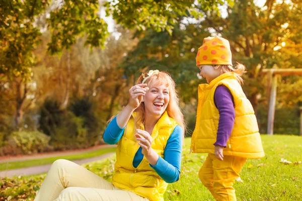 Hija dando a su madre una hoja de otoño — Foto de Stock