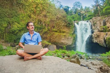 Man using his laptop in a jungle clipart