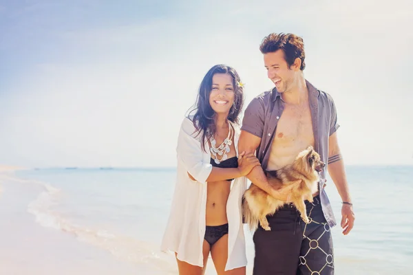 Coppia che tiene un cucciolo su una spiaggia — Foto Stock