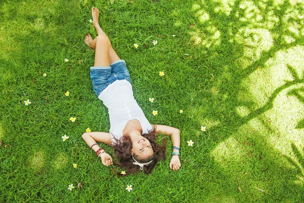 Jovem mulher relaxante em uma grama — Fotografia de Stock