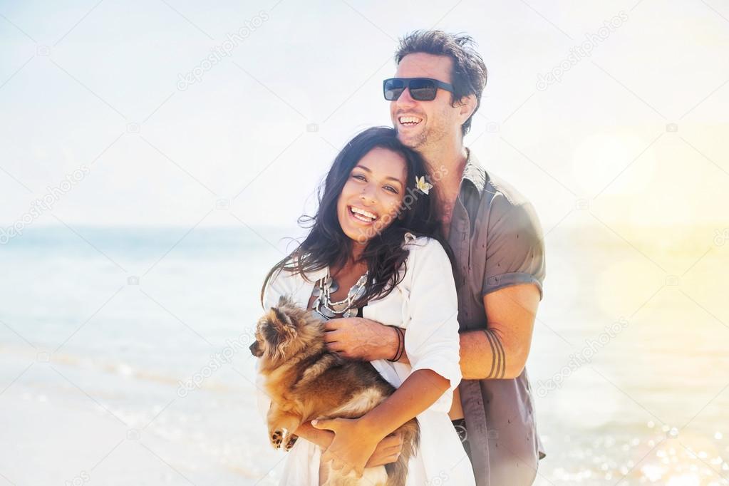 couple holding a puppy on a beach