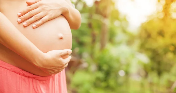 Mujer embarazada tocando su desnudo abdomen — Foto de Stock