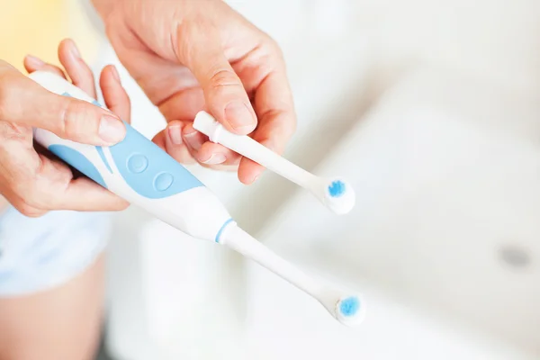 Woman replacing a nozzle of an electric brushes — Stock Photo, Image