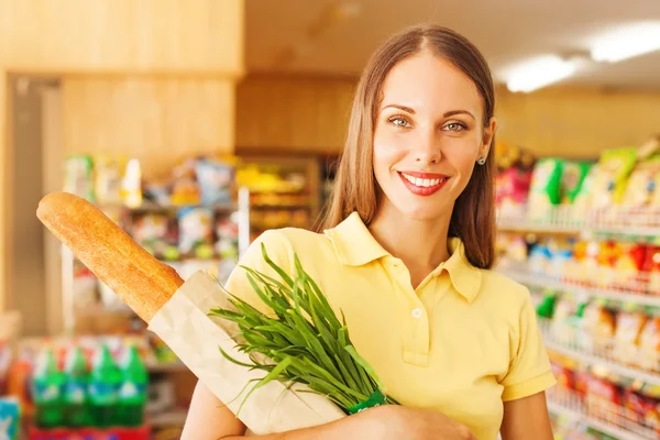Kobieta kupno chleba i cebuli w supermarkecie, patrząc na kamery — Zdjęcie stockowe