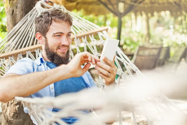 Man met mobiele telefoon in hangmat — Stockfoto