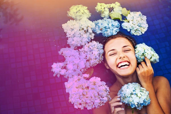 Woman in swimming pool full of hortensia — Stock Photo, Image