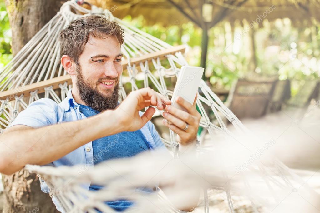 man using mobile phone in  hammock