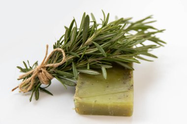 Bir parça el yapımı yeşil sabun, doğal kozmetik ürünleri olmayan biberiyenin yanında yatıyor.