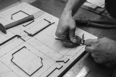 Efendinin elleri ölçü alır. Atölye çalışması, bir matrisin üretimi ve geliştirilmesi, karton ve kağıt kapları kestiği için ölüyor. Tahta ve metal. El yapımı. Uzayı kopyala Siyah ve beyaz