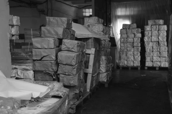 pallets with boxes, products are packed in paper and stacked in piles at the finished goods warehouse. Cardboard factory concept. Selective focus. Black and white