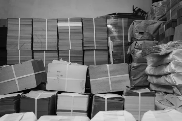 pallets with boxes, products are packed in paper and stacked in piles at the finished goods warehouse. Cardboard factory concept. Selective focus. Black and white.
