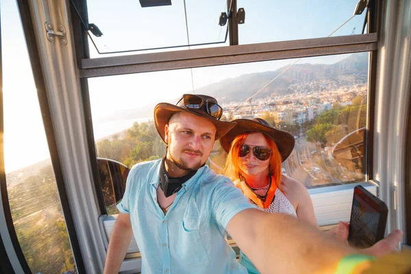 An tourists woman and man travel together, do selfie on a mobile phone in the cockpit of a funicular during a summer holiday at sea. Alanya, Turkey 2020