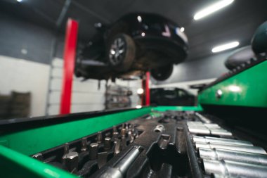 Aygıtlara yakın ayrıntılı görünüm. Alet çantası. Arka planda asansörde bir araba var. Tamir ve servis. Seçici odak