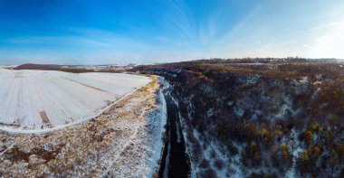 Eski bir kalenin havadan görünüşü, köy manzarası. Kar ve kış. Nehir ve orman. Geniş ekran panorama. Sataniv, Ukrayna