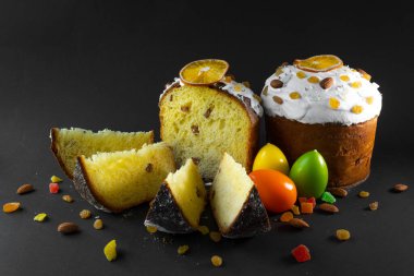 Siyah arka planda geleneksel Paskalya pastası. Göçmen, şekerli meyve, kuru üzüm, dekoratif renkli yumurta. Bölgesel görüş, dilimler, parçalar. Ortodoks muamelesi. Boşluğu kopyala