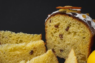 Siyah arka planda geleneksel Paskalya pastası. Göçmen, şekerli meyve, kuru üzüm, dekoratif renkli yumurta. Bölgesel görüş, dilimler, parçalar. Yakın plan. Boşluğu kopyala