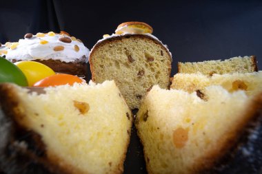 Yakın çekim görüntüsü. Siyah arka planda geleneksel Paskalya pastası. Göçmen, şekerli meyve, kuru üzüm, dekoratif renkli yumurta. Bölgesel görüş, dilimler, parçalar. Ortodoks muamelesi.