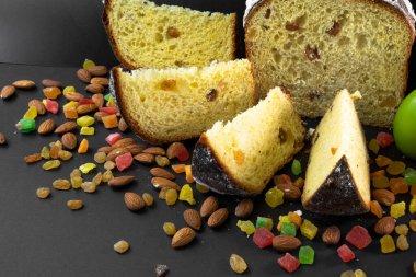 Siyah arka planda geleneksel Paskalya pastası. Göçmen, şekerli meyve, kuru üzüm, dekoratif renkli yumurta, mumlar yanıyor. Bölgesel görüş, dilimler, parçalar. Ortodoks muamelesi. Yakın plan.