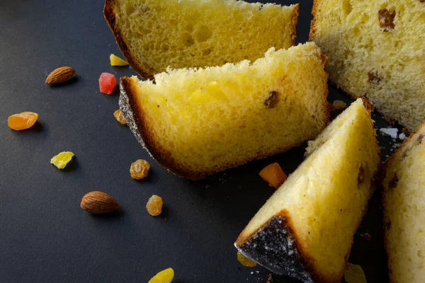 Siyah arka planda geleneksel Paskalya pastası. Göçmen, şekerli meyve, kuru üzüm, dekoratif renkli yumurta. Bölgesel görüş, dilimler, parçalar. Ortodoks muamelesi. Yakın plan.