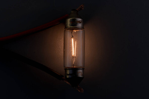 Car classic halogen bulb. Filament, glass and metal, high energy consumption. Black background. interior lighting. energized, working condition. Lights up