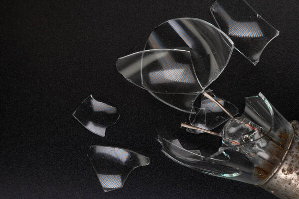 сломанная автомобильная лампочка на черном фоне. Филамент и осколки стекла. Копирование пространства