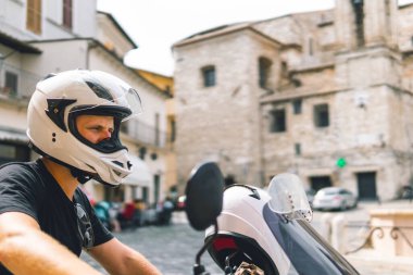 Beyaz kasklı yakışıklı adam eski macera motosikletinin üzerinde oturuyor. Seyahat ve tatil konsepti. Özgürlük için. Park yeri arıyorum. Narni, İtalya