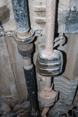 Gövdenin altındaki araç egzoz borusu, katalizör, rezonatör, egzoz sistemi. Eski parçalar tamir ve yenileme gerektirir. Araba servisi ve bakım. kardan ve dış rota