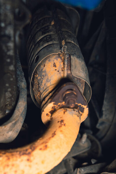 Vehicle underbody exhaust pipe, catalyst, resonator, exhaust system. Old parts require repair and replacement. Car service and maintenance. Standards and technical condition. selective focus