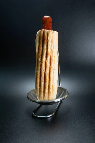 Siyah arka planda Fransız sosislisi. Fast food pastanesi ürünü. Yapım. Dikey fotoğraf.