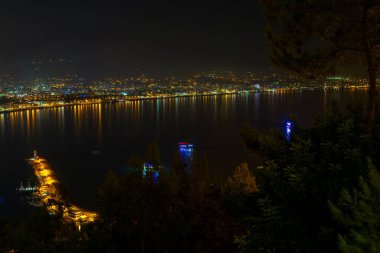 Alanya Körfezi 'ndeki Kizil Kule kulesi, Antalya' nın Antalya ilçesindeki yarımadadan görülen tekne ve gemiler. Ünlü turizm merkezi. Gece şehir manzarası.