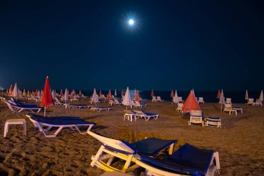 Gece kumsalı, kumsal ve deniz manzarası, şemsiyeler ve güneş panzeleri. Ay ışığı. Ceset yok. Hindi Alanya kıyısı ve seti. Boşluğu kopyala