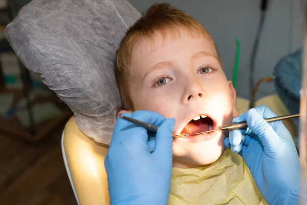 No consultório odontológico, uma criança de 7 anos é examinada por ferramentas especiais — Fotografia de Stock